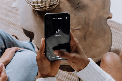 Maini tinand in mana un smartphone cu aplicatia Tik Tok instalata