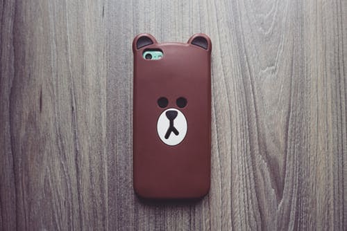 husa urs brun pentru smartphone pe un fundal maro