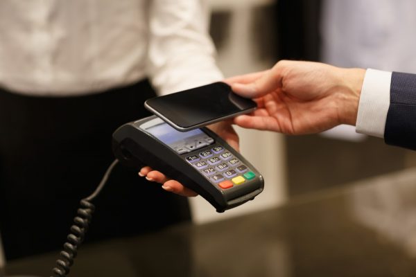 Barbat facand o plata contactless cu telefonul